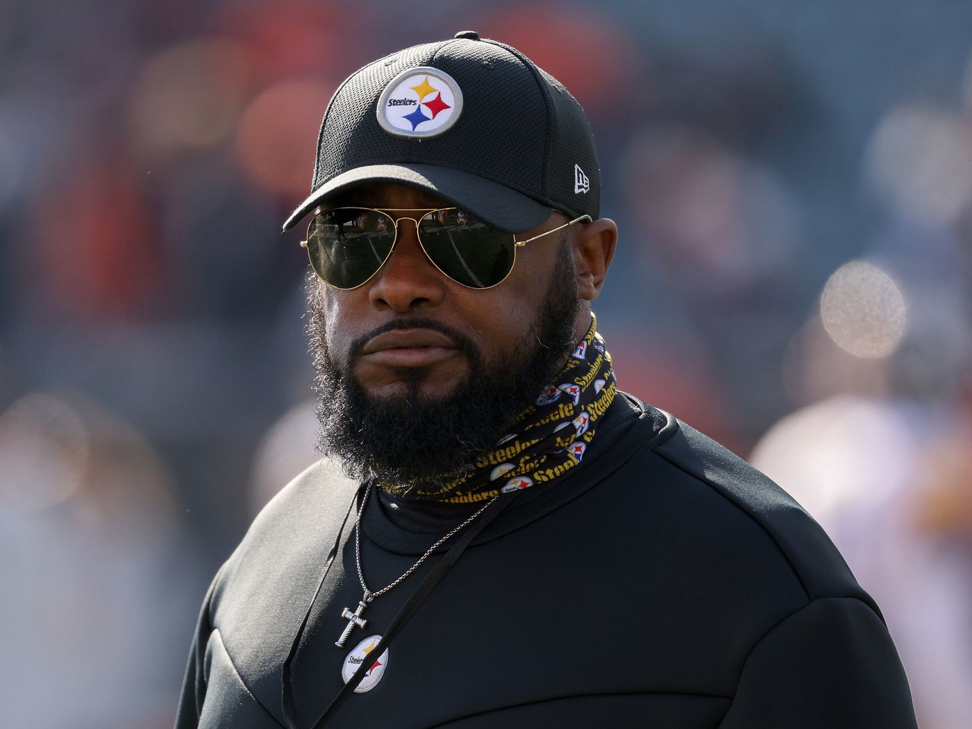 Mike Tomlin wearing a black shirt, cap, and sunglasses
