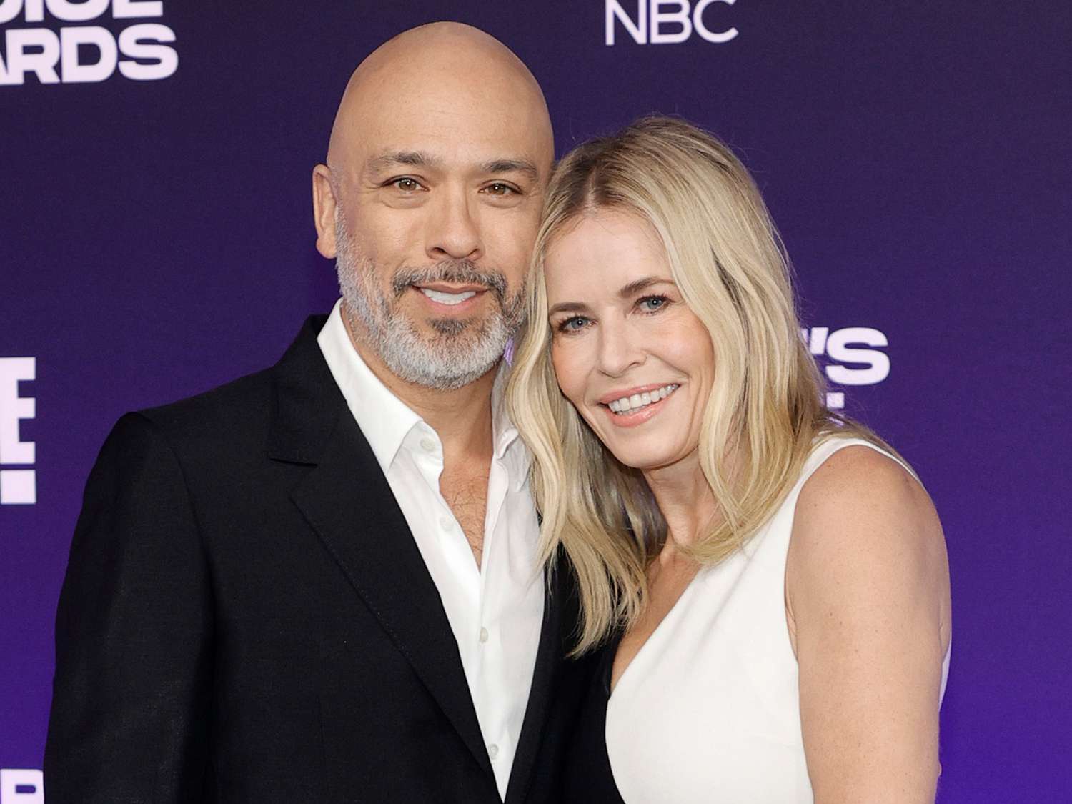 Jo Koy wearing a blck suit and Chelsea Handler wearing a black and white dress