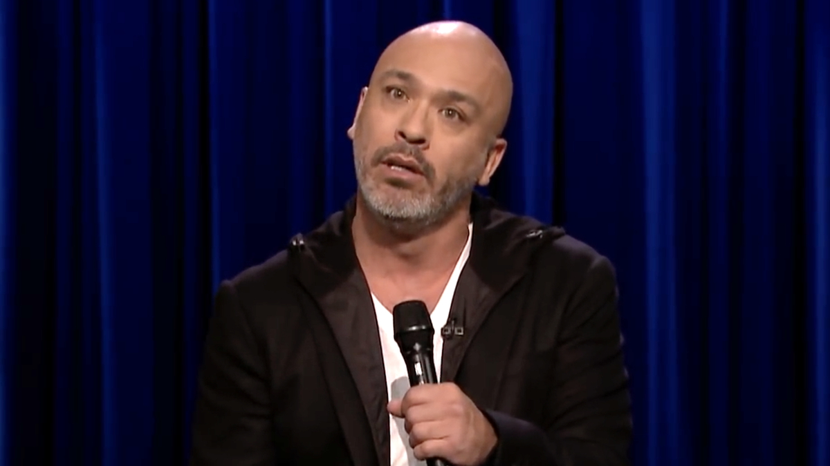 Jo Koy wearing a black jaccket while holding a mic