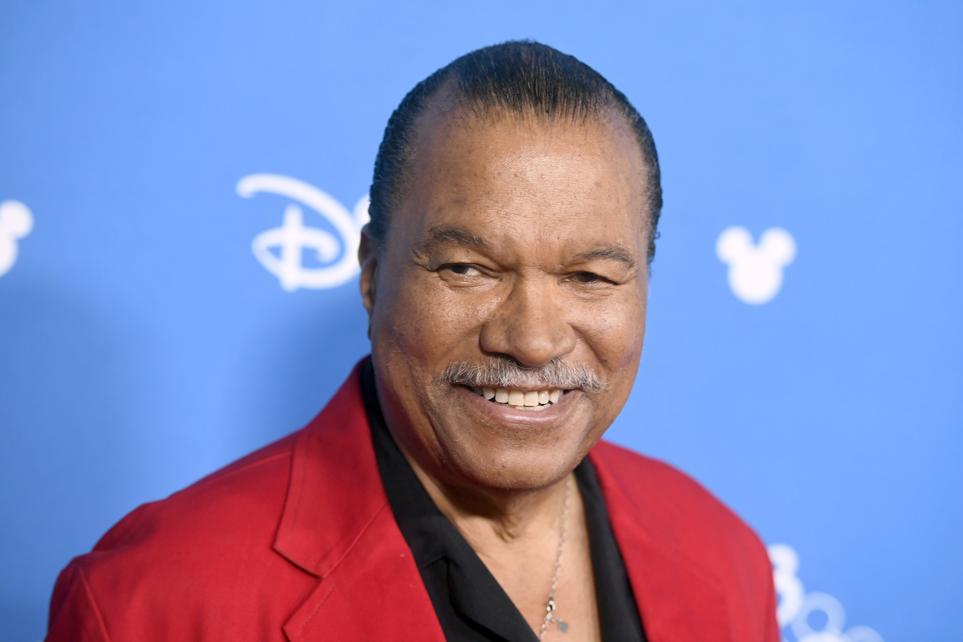Billy Dee Williams wearing a red suit
